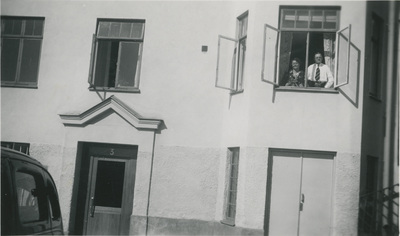 Två personer i fönstret på ett lägenhetshus