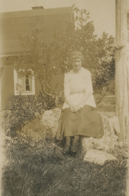 En kvinna sitter i en trädgård