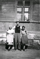 En man och två kvinnor framför en husvägg