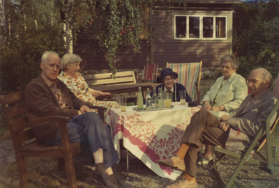 Gruppfoto med makarna Höglund utanför en stuga