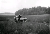 Två män med en traktor på en åker