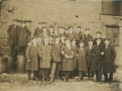 Gruppfoto på män framför tegelbyggnad