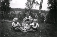 En kvinna med två barn i en trädgård