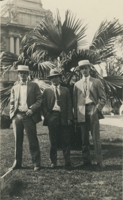 Tre män framför en palm