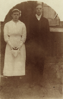 En ung flicka och pojke  framför en husvägg
