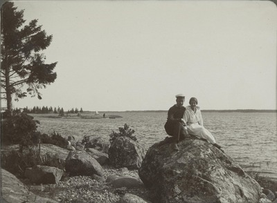 Man och kvinna sitter på en sten vid havet