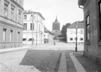 Hörnet Slottsgatan/Västra Storgatan, Stora torget i Nyköping, med västra klockstapeln i bakgrunden, 1890-tal