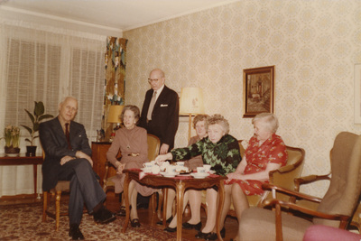 Gruppfoto med makarna Höglund vid ett fikabord