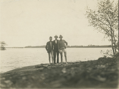 Tre personer på en klippa vid havet