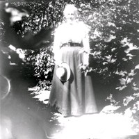 Kvinna med halmhatt och lång kjol i trädgården