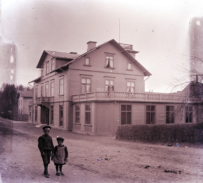 Barn framför ett stort trähus, tidigt 1900-tal