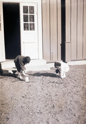 Två barn leker framför ett hus