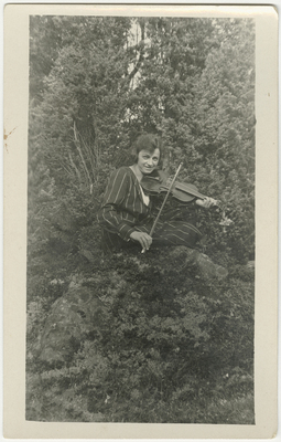 Kvinna spelar fiol i skogen