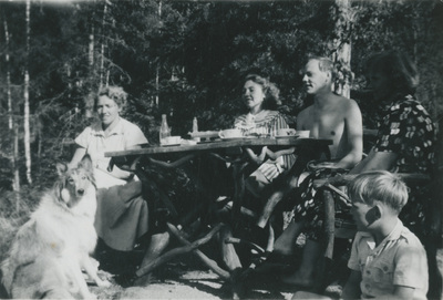 Fem personer fikar vid ett picknickbord