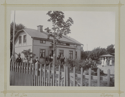 Gruppfotografi i trädgård framför hus tidigt 1900-tal
