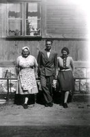 En man och två kvinnor framför en husvägg