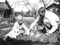 En pappa och dotter med kaniner i gräset.