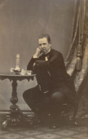 Ateljéfoto, sittande man vid bord med karaff och glas, 1860-tal