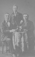 Tre män vid ett bord med flaskor