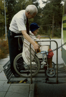Chaufför hjälper en rullstolsburen äldre dam in i en färdtjänstbuss